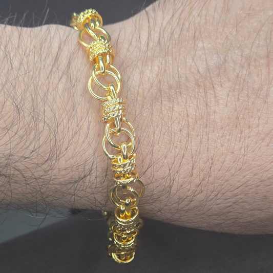 Gold bracelet on a wrist against a dark background