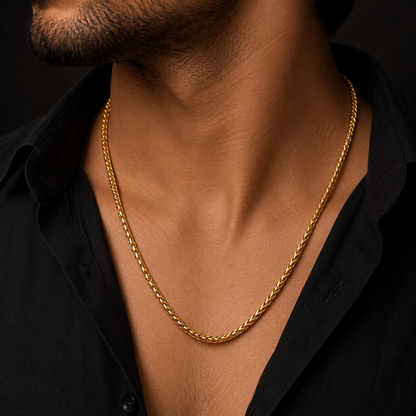 A close-up of a man's neck and chest wearing a gold rope chain necklace over a black button-down shirt.