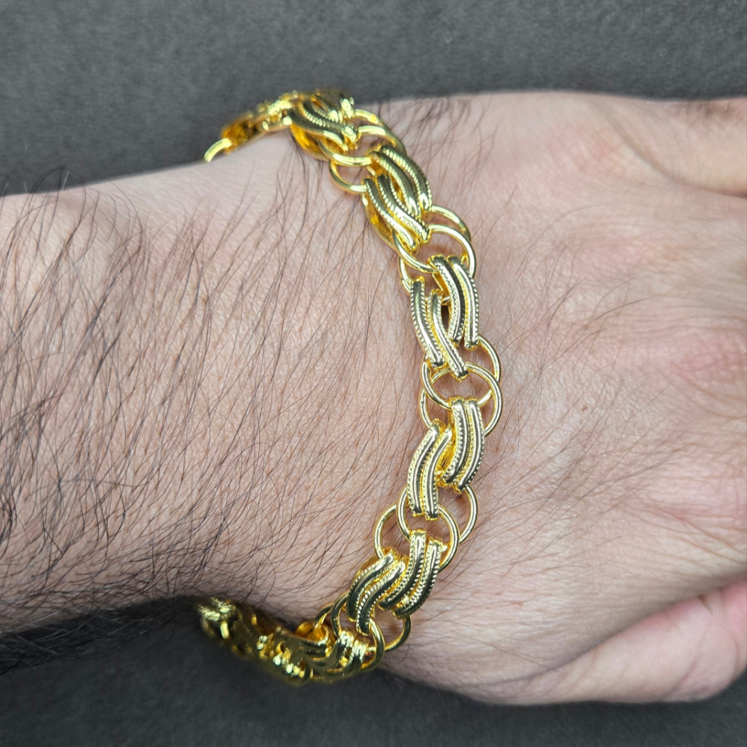 Gold bracelet on a wrist against a gray background