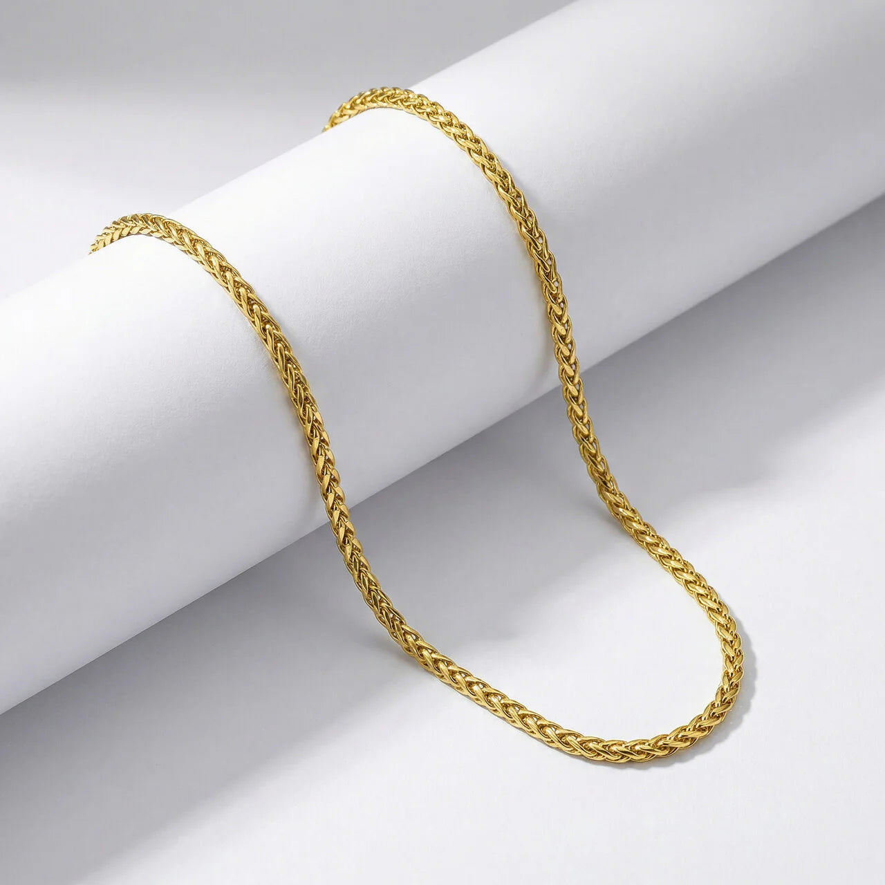 Gold chain on a white cylindrical object with a gray background